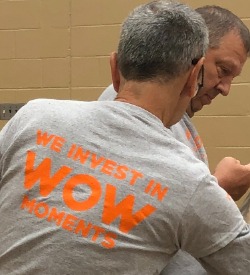 Man's back with a shirt that says We Invest in WOW Moments