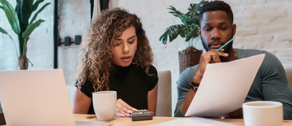 Couple sitting at table reviewing a piece of paper and looking at calculator