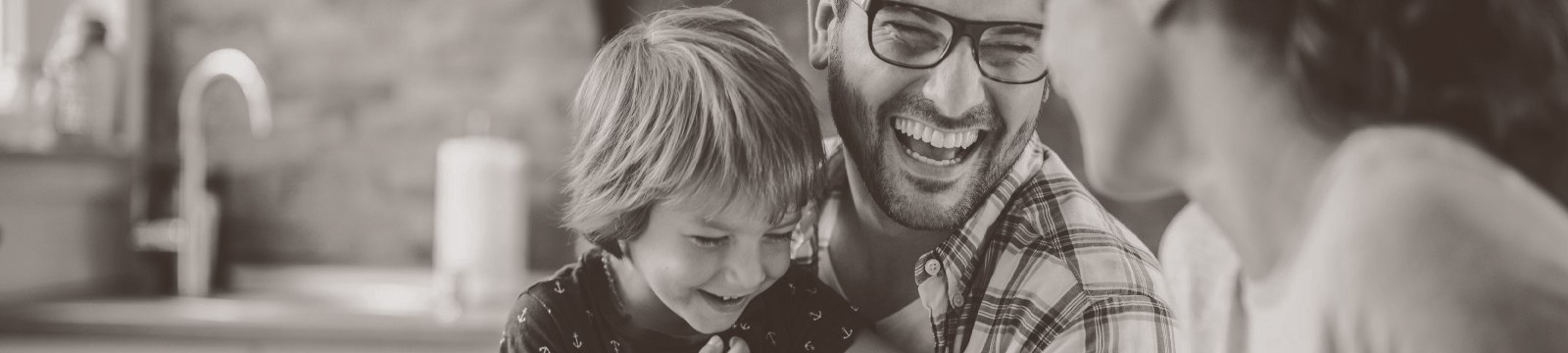 Family of three laugh with one another.