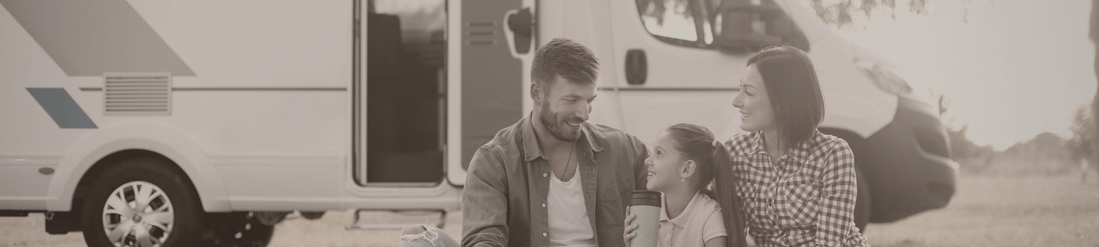 Family of 3 sitting outside their recreational vehicle.