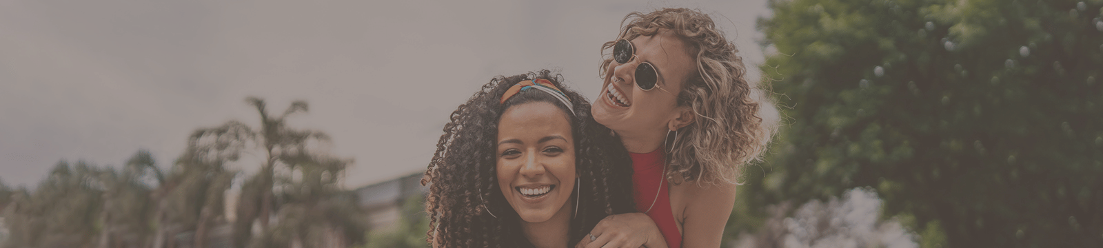 Two girls smiling with trees behind them